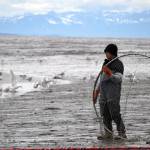 A fisher stands with his net at the ready on the bank of the Kenai River in Kenai, Alaska, on Wednesday, July 10, 2024. (Jake Dye/Peninsula Clarion)