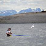 A fisher stands with net extended in the Kenai River in Kenai, Alaska, on Wednesday, July 10, 2024. (Jake Dye/Peninsula Clarion)