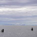 Fishers stand with nets extended in the Kenai River in Kenai, Alaska, on Wednesday, July 10, 2024. (Jake Dye/Peninsula Clarion)