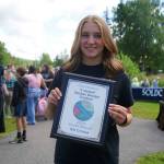 Isla Crouse stands with her award for winning the City of Soldotnas I Voted Sticker Design Contest at the Soldotna Progress Days Block Party in Parker Park in Soldotna, Alaska, on Saturday, July 27, 2024. (Jake Dye/Peninsula Clarion)