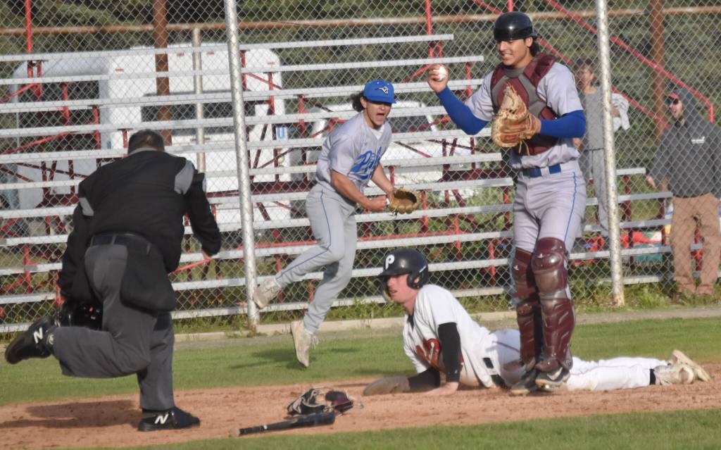 Peninsula Oilers Aidan Sullivan is tagged out by Anchorage Glacier Pilots catcher Rodrigo Barajas on Monday, July 29, 2024, at Coral Seymour Memorial Park in Kenai, Alaska. Sullivan was trying to score the winning run in the bottom of the ninth. Pilots pitcher Evan Chadwick celebrates in the background. (Photo by Jeff Helminiak/Peninsula Clarion)