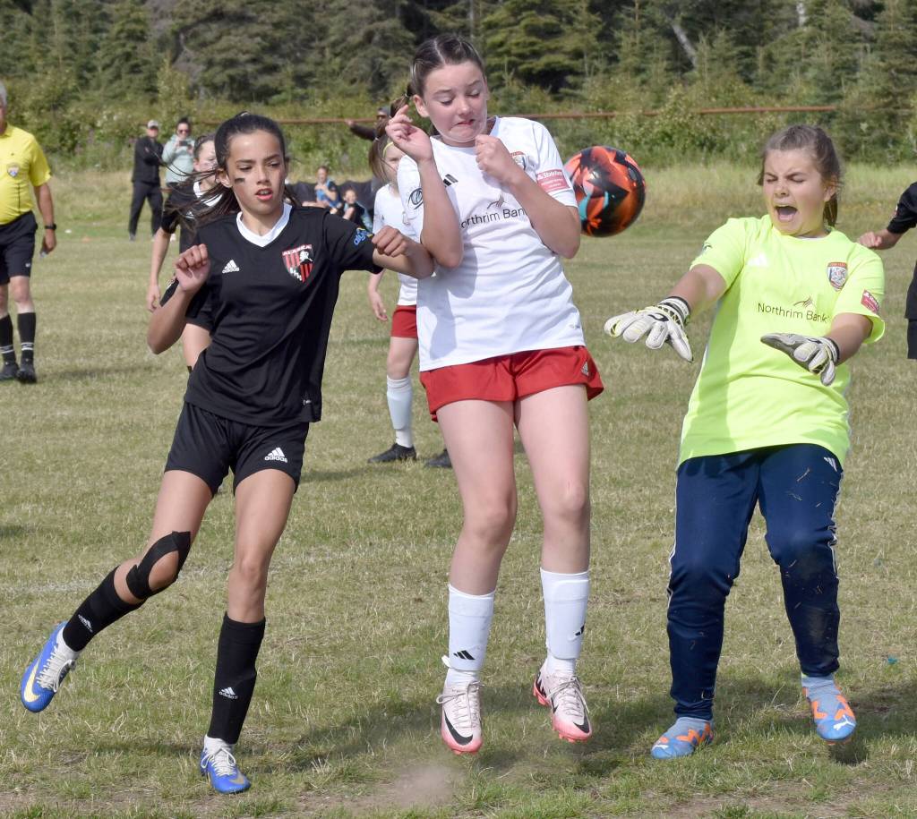 Lily Hough of the Kenai Kicks challenges Kennedy Owens and goalie Dayley Luff of the Cook Inlet Soccer Club for the ball Saturday, Aug. 3, 2024, at the Kenai Sports Complex in Kenai, Alaska, in a U13 Alaska Youth State Cup game. (Photo by Jeff Helminiak/Peninsula Clarion)