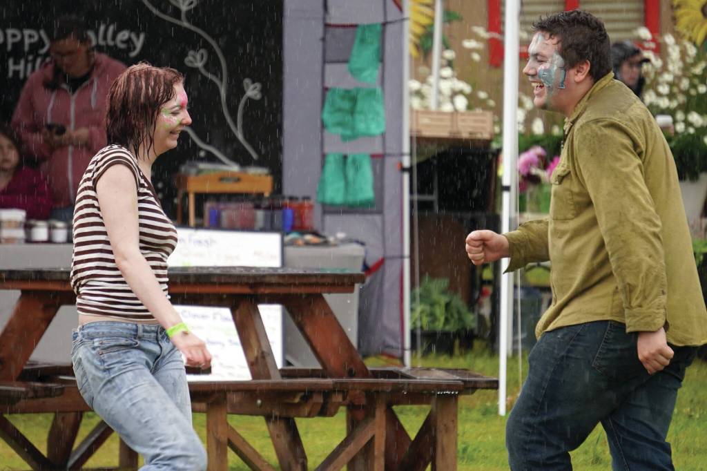 Attendees dance in the rain at the Kenai Peninsula Fair in Ninilchik, Alaska, on Friday, Aug. 11, 2023. (Jake Dye/Peninsula Clarion)