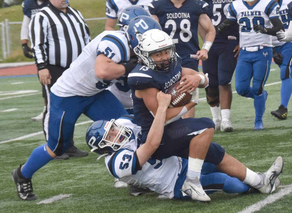 Soldotna's Lokeni Wong fights for yards against Luke Sena (51) and Jason Reese of Palmer on Friday, Aug. 16, 2024, at Justin Maile Field at Soldotna High School in Soldotna, Alaska. (Photo by Jeff Helminiak/Peninsula Clarion)