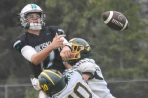 Nikiski's Ethan Ellis passes under pressure from Seward's Ronan Bickling and Emerson Cross (10) on Saturday, Aug. 17, 2024, at Nikiski Middle-High School in Nikiski, Alaska. (Photo by Jeff Helminiak/Peninsula Clarion)
