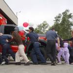 Kenai Fire Department staff and other attendees push a new ambulance into the garage at the Kenai Public Safety Building in Kenai, Alaska, on Saturday, Aug. 17, 2024. (Jake Dye/Peninsula Clarion)