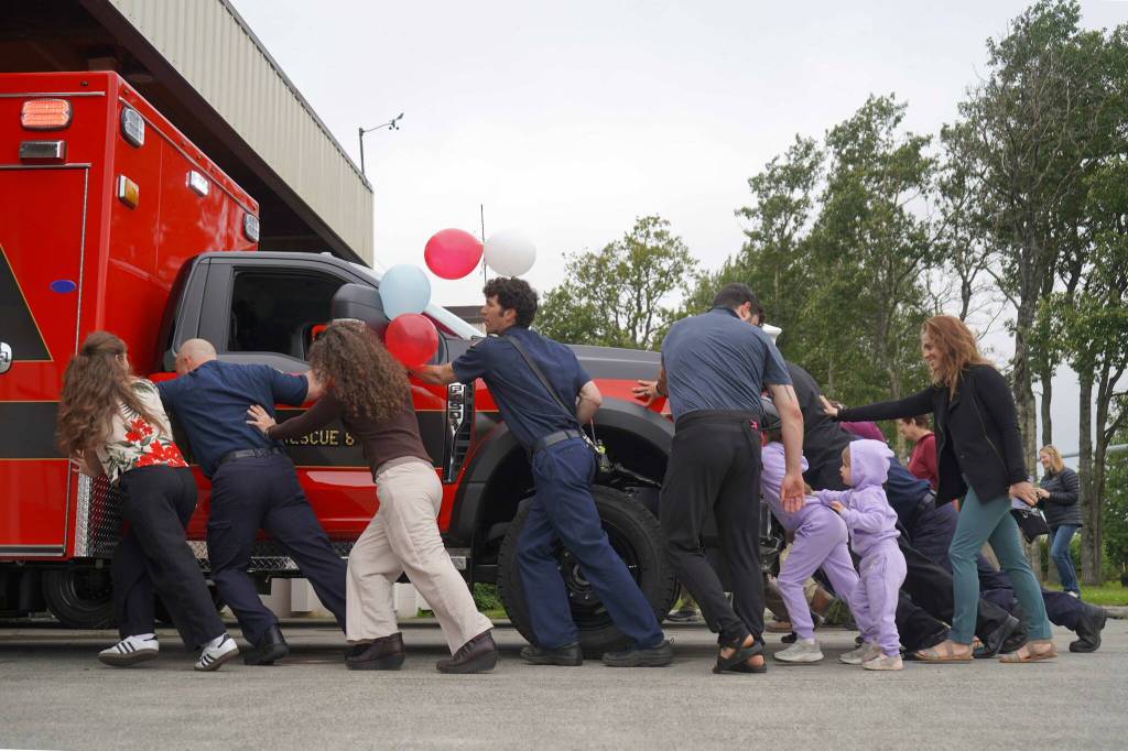 Kenai Fire Department staff and other attendees push a new ambulance into the garage at the Kenai Public Safety Building in Kenai, Alaska, on Saturday, Aug. 17, 2024. (Jake Dye/Peninsula Clarion)