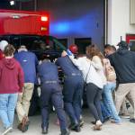 Kenai Fire Department staff and other attendees push a new ambulance into the garage at the Kenai Public Safety Building in Kenai, Alaska, on Saturday, Aug. 17, 2024. (Jake Dye/Peninsula Clarion)
