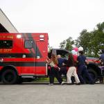 Kenai Fire Department staff and other attendees push a new ambulance into the garage at the Kenai Public Safety Building in Kenai, Alaska, on Saturday, Aug. 17, 2024. (Jake Dye/Peninsula Clarion)
