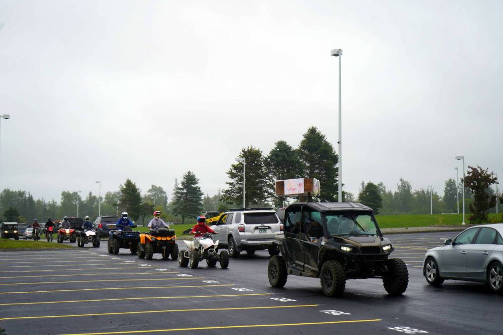 ATVs and other off-road vehicles roll through the Nikiski Middle/High School parking lot in Nikiski, Alaska, during the Community Ride for Parking Policy Change on Saturday, Aug. 17, 2024. (Jake Dye/Peninsula Clarion)