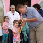 Kenai Mayor Brian Gabriel is joined by one of the children of the Gutierrez family as they cut the ribbon to open The Glaze in Kenai, Alaska, on Wednesday, Sept. 4, 2024. (Jake Dye/Peninsula Clarion)