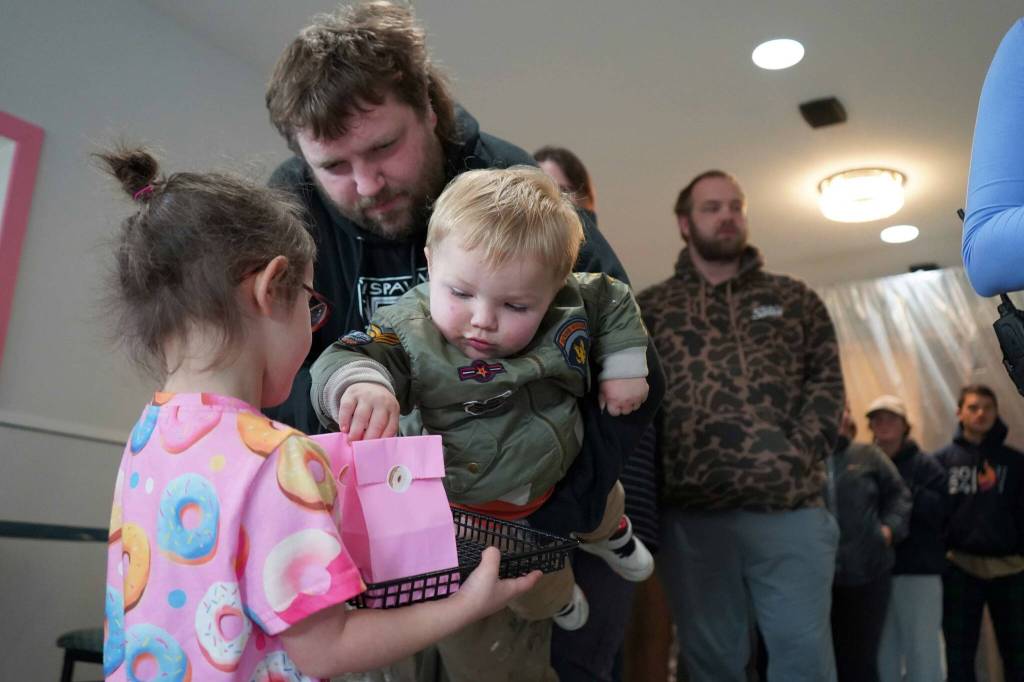 Children distribute bags of doughnut holes during a ribbon-cutting event for The Glaze in Kenai, Alaska, on Wednesday, Sept. 4, 2024. (Jake Dye/Peninsula Clarion)