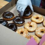 Abi Gutierrez fills a box of doughnuts during a ribbon-cutting event for The Glaze in Kenai, Alaska, on Wednesday, Sept. 4, 2024. (Jake Dye/Peninsula Clarion)