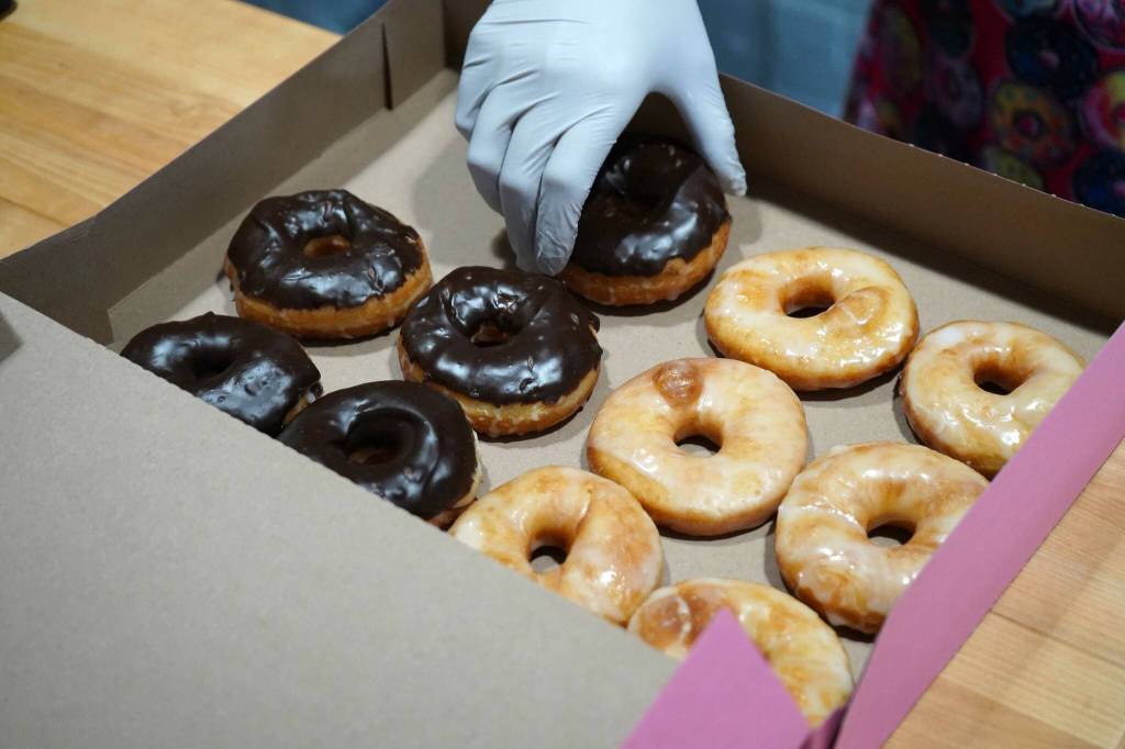 Abi Gutierrez fills a box of doughnuts during a ribbon-cutting event for The Glaze in Kenai, Alaska, on Wednesday, Sept. 4, 2024. (Jake Dye/Peninsula Clarion)