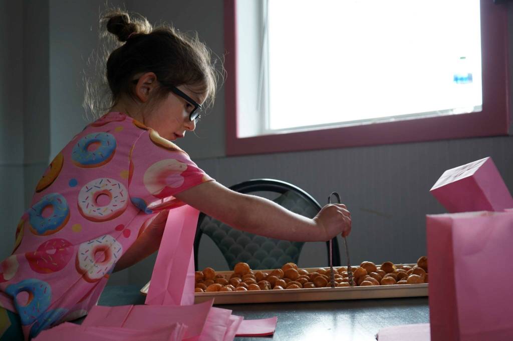 Children fill bags of doughnut holes during a ribbon-cutting event for The Glaze in Kenai, Alaska, on Wednesday, Sept. 4, 2024. (Jake Dye/Peninsula Clarion)