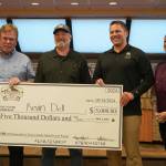 Kevin Dell, center left, is awarded a $5,000 novelty check for landing the adult grand-prize salmon in the Eighth Annual Kenai Silver Salmon Derby by Kenai Mayor Brian Gabriel, a representative of Marathon Petroleums Kenai Refinery and Kenai Chamber of Commerce Executive Director Samantha Springer during a meeting of the Kenai City Council on Wednesday, Sept. 18, 2024, in Kenai, Alaska. (Jake Dye/Peninsula Clarion)