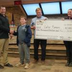 Carter Romero, center left, is awarded a $1,000 novelty check for landing the youth grand-prize salmon in the Eighth Annual Kenai Silver Salmon Derby by Kenai Mayor Brian Gabriel, a representative of Marathon Petroleums Kenai Refinery and Kenai Chamber of Commerce Executive Director Samantha Springer during a meeting of the Kenai City Council on Wednesday, Sept. 18, 2024, in Kenai, Alaska. (Jake Dye/Peninsula Clarion)