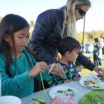 Children prepare edible veggie necklaces during the Harvest Moon Local Food Festival at Soldotna Creek Park in Soldotna, Alaska, on Saturday, Sept. 21, 2024. (Jake Dye/Peninsula Clarion)