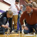 KPBSD Superintendent Clayton Holland, right, watches a contestant carelfully place a weight atop their tower during the Spontaneous Challenge portion of the Mind-A-Mazes competition at Skyview Middle School near Soldotna, Alaska, on Saturday, Oct. 19, 2024. (Jake Dye/Peninsula Clarion)