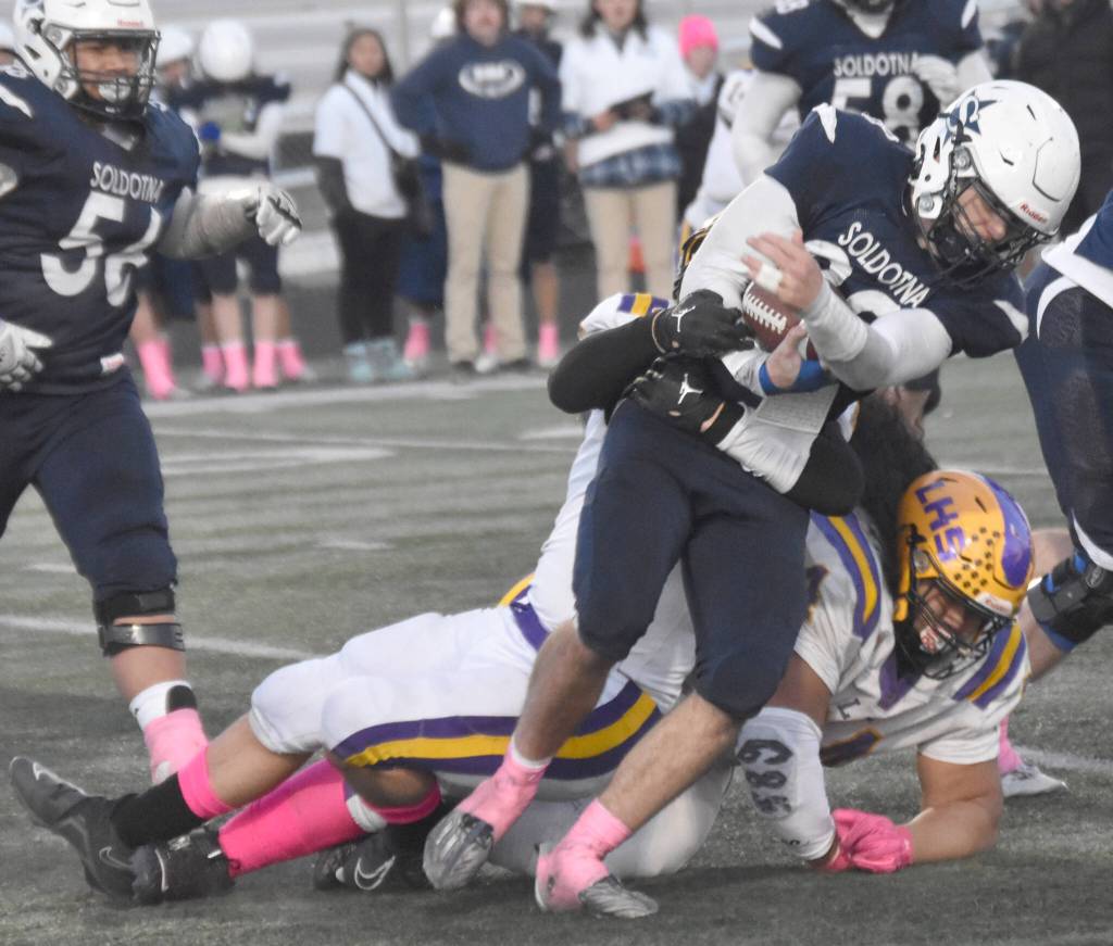 Soldotnas Wyatt Faircloth runs against Lathrops Luke Skinner and Zedekiah Fanene on Saturday, Oct. 26, 2024, at the First National Bowl Division II title game at Pride Field at Colony High School in Palmer, Alaska. (Photo by Jeff Helminiak/Peninsula Clarion)