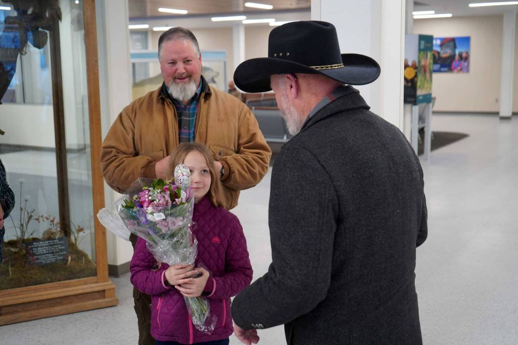 Rose Burke, center left, is celebrated for winning the U.S. Capitol Christmas Tree essay contest by Connections Homeschool Principal Douglas Hayman, right, at the Kenai Municipal Airport in Kenai, Alaska, on Friday, Nov. 1, 2024. (Jake Dye/Peninsula Clarion)