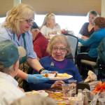Kenai City Council member and Hilcorp volunteer Victoria Askin delivers a Thanksgiving meal to Ava Bassett during the Hilcorp Areawide Senior Thanksgiving Luncheon in the Kenai Senior Center banquet hall in Kenai, Alaska, on Friday, Nov. 22, 2024. (Jake Dye/Peninsula Clarion)
