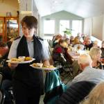 A Kenai Civil Air Patrol cadet delivers Thanksgiving meals to seniors during the Hilcorp Areawide Senior Thanksgiving Luncheon in the Kenai Senior Center banquet hall in Kenai, Alaska, on Friday, Nov. 22, 2024. (Jake Dye/Peninsula Clarion)