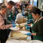 Kenai Peninsula Borough Mayor Peter Micciche and Hilcorp volunteers prepare plates for delivery to tables during the Hilcorp Areawide Senior Thanksgiving Luncheon in the Kenai Senior Center banquet hall in Kenai, Alaska, on Friday, Nov. 22, 2024. (Jake Dye/Peninsula Clarion)
