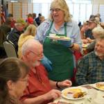 Kenai City Council member and Hilcorp volunteer Victoria Askin delivers Thanksgiving meals during the Hilcorp Areawide Senior Thanksgiving Luncheon in the Kenai Senior Center banquet hall in Kenai, Alaska, on Friday, Nov. 22, 2024. (Jake Dye/Peninsula Clarion)