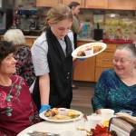 Kenai Civil Air Patrol Cadet Elodi Frisk delivers Thanksgiving meals to seniors during the Hilcorp Areawide Senior Thanksgiving Luncheon in the Kenai Senior Center banquet hall in Kenai, Alaska, on Friday, Nov. 22, 2024. (Jake Dye/Peninsula Clarion)