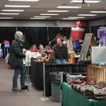 Jonas Oyoumick/Peninsula Clarion
Henry Dera, of Crooked Creek Birch, chats with shoppers at the 33rd Annual Holiday Bazaar at the Soldotna Regional Sports Complex on Friday.