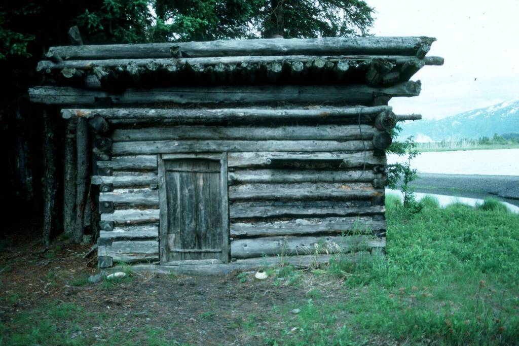 The log shed at Blakes Place on the north shore on Tustumena Lake, near the outlet of Indian Creek. Kerri Dolph holed up here for several days after the death of her husband John. (Photo by Clark Fair, 1985)