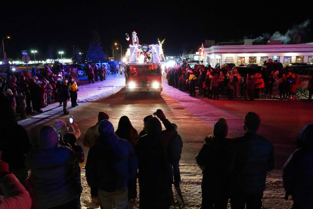 Santa Claus waves at paradegoers from atop a Kenai Fire Department engine on Frontage Street in Kenai, Alaska, as part of the Electric Lights Parade on Friday, Nov. 29, 2024. (Jake Dye/Peninsula Clarion)