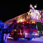 Santa Claus waves at children from atop a Kenai Fire Department engine on Frontage Street in Kenai, Alaska, as part of the Electric Lights Parade on Friday, Nov. 29, 2024. (Jake Dye/Peninsula Clarion)
