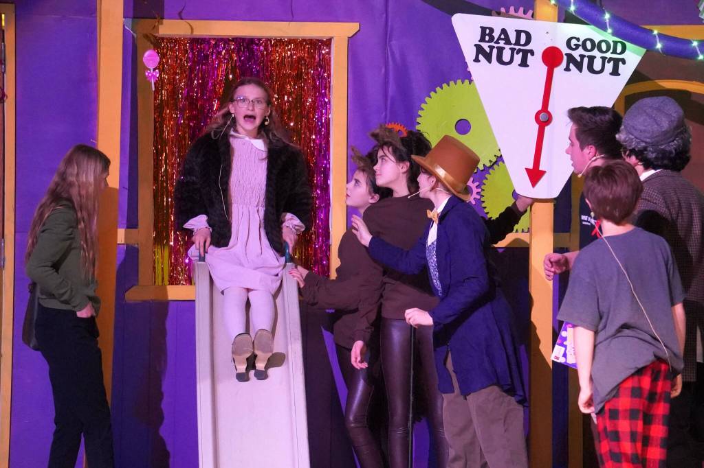 Adelaide Denison, on the slide, and the cast of Nikiski Bulldog Theatres Willy Wonka Jr. rehearse at Nikiski Middle/High School on Tuesday, Dec. 3, 2024. (Jake Dye/Peninsula Clarion)