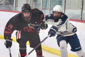 Juneau-Douglas senior Ike Puustinen (16) works for a puck against Soldotna's Eli Settlemyer (28) during a 4-3 Crimson Bears loss to the visiting Stars at Treadwell Ice Arena in Juneau, Alaska, on Friday, Dec. 13, 2024. (Klas Stolpe / Juneau Empire)