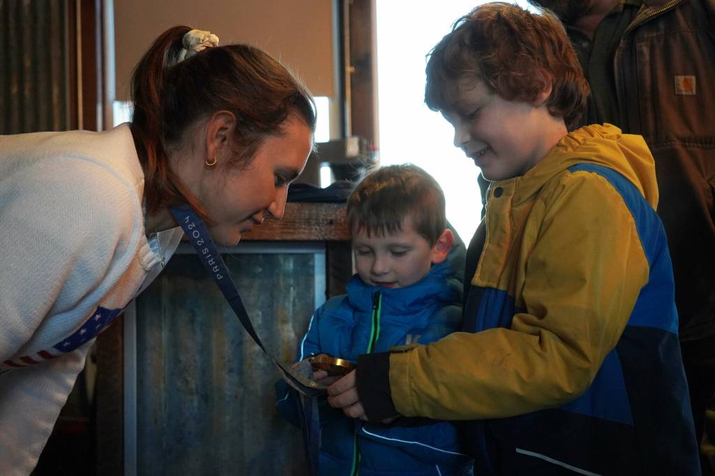 Kristen Faulkner, who won two gold medals for cycling at the Paris 2024 Olympics, speaks to James Elam and his brothers during a meet and greet hosted by the Kenai and Soldotna chambers of commerce at the Cannery Lodge in Kenai, Alaska, on Saturday, Dec. 28, 2024. (Jake Dye/Peninsula Clarion)