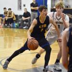 Cook Inlet Academys Alek McGarry drives on Ninilchiks Andon McCorison on Tuesday, Jan. 8, 2025, at Ninilchik School in Ninilchik, Alaska. (Photo by Jeff Helminiak/Peninsula Clarion)