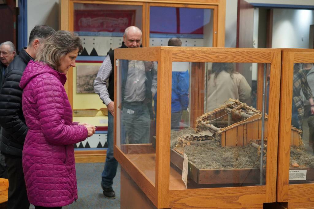 Attendees inspect a displayed model of a traditional Denaina home called a nichil during the grand reopening of the cultural center at the Kenai Chamber of Commerce and Visitor Center in Kenai, Alaska, on Wednesday, Jan. 15, 2025. (Jake Dye/Peninsula Clarion)