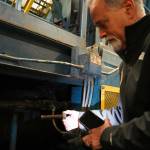 Kenai Peninsula Borough Mayor Peter Micciche holds one of the large bolts that formerly connected the baler ram to the larger machine at the Central Peninsula Landfill in Soldotna, Alaska, on Thursday, Jan. 16, 2025. (Jake Dye/Peninsula Clarion)