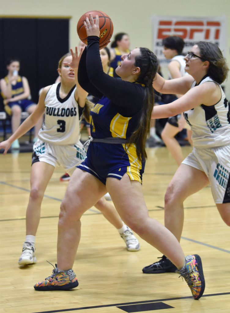 Ninilchiks Rylee Lemons drives on Nikiskis Abby White and Natalie Huntsman at the 36th Annual Rus Hitchcock Nikiski Tip Off Tournament on Thursday, Jan. 16, 2025, at Nikiski Middle-High School in Nikiski, Alaska. (Photo by Jeff Helminiak/Peninsula Clarion)