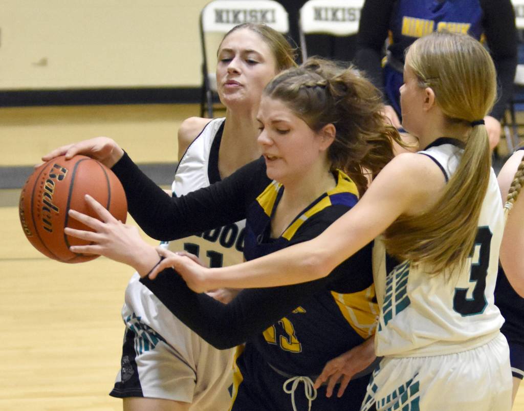 Ninilchiks Lucy Reynolds grabs the ball in front of Nikiskis Blakeley Jorgensen and Abby White at the 36th Annual Rus Hitchcock Nikiski Tip Off Tournament on Thursday, Jan. 16, 2025, at Nikiski Middle-High School in Nikiski, Alaska. (Photo by Jeff Helminiak/Peninsula Clarion)