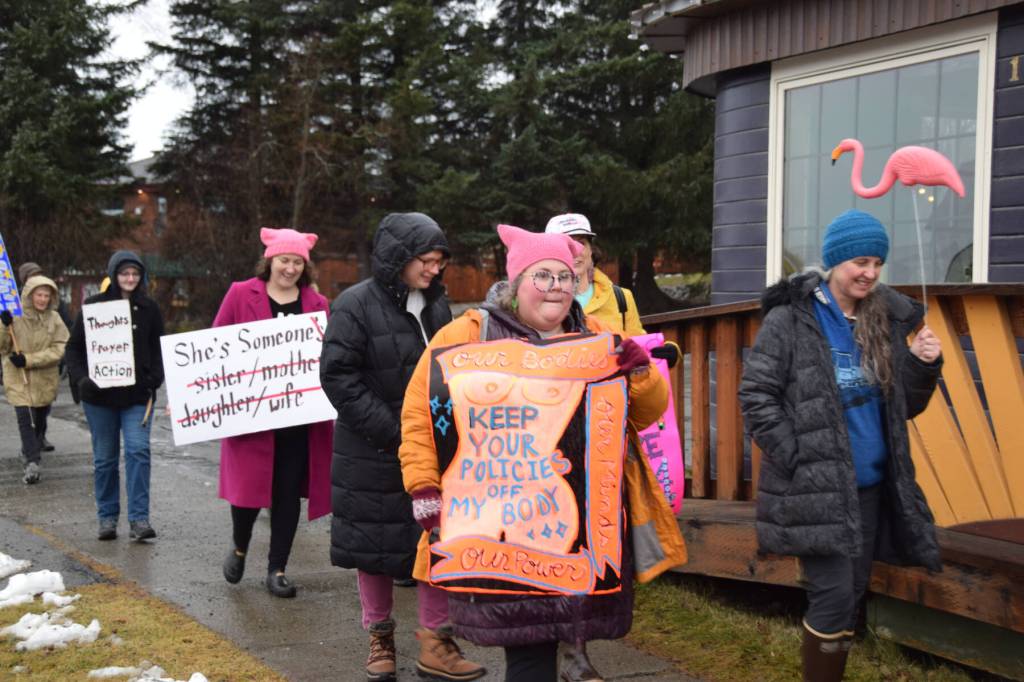 Community members participating in the Homer Womens March on Pioneer Avenue on Saturday, Jan. 18, 2025, in Homer, Alaska, carry signs saying Our Bodies, Our Minds, Our Power, Keep Your Policies off My Body and other slogans. (Delcenia Cosman/Homer News)