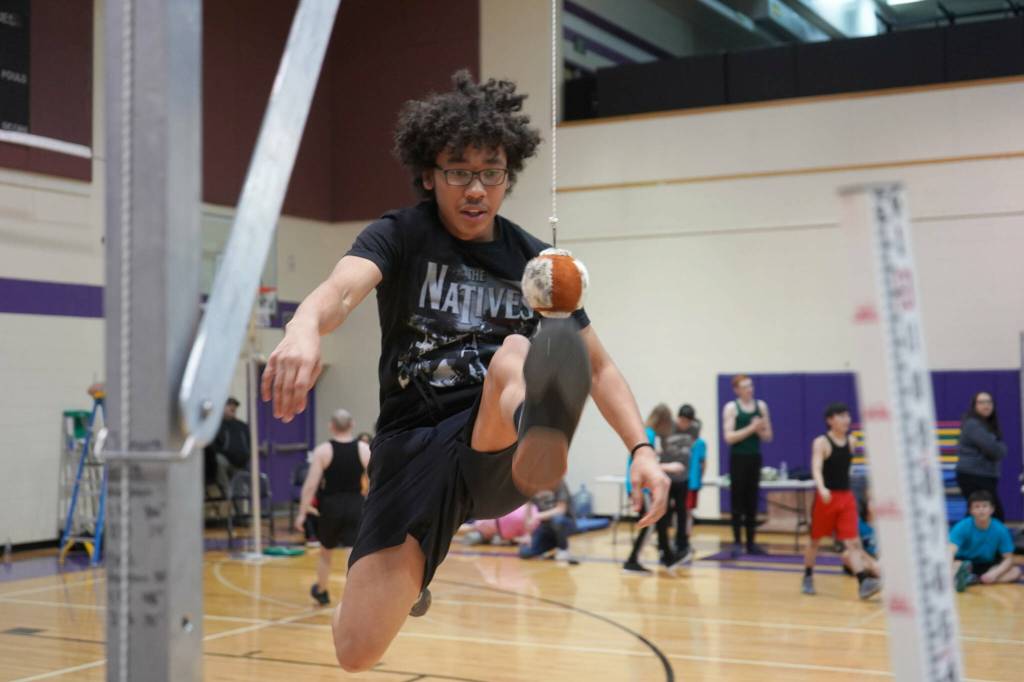 An athlete leaps up to perform the one-foot high kick during the Kahtnuhtana Hey Chiula Native Youth Olympics Invitational at Skyview Middle School near Soldotna, Alaska, on Sunday, Jan. 26, 2025. (Jake Dye/Peninsula Clarion)
