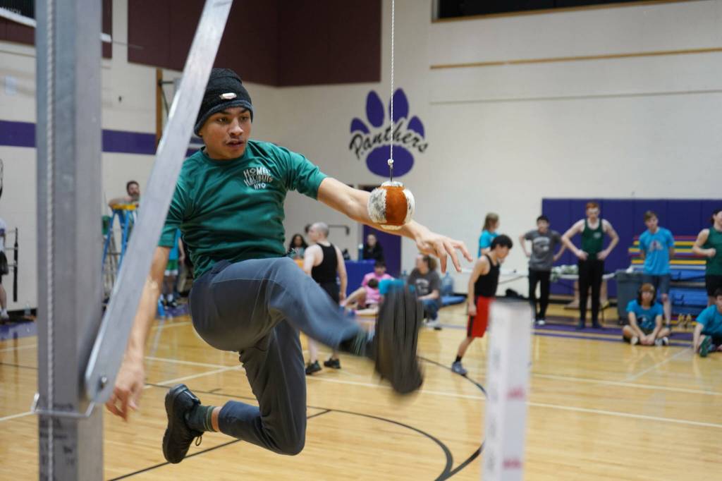 An athlete leaps up to perform the one-foot high kick during the Kahtnuhtana Hey Chiula Native Youth Olympics Invitational at Skyview Middle School near Soldotna, Alaska, on Sunday, Jan. 26, 2025. (Jake Dye/Peninsula Clarion)