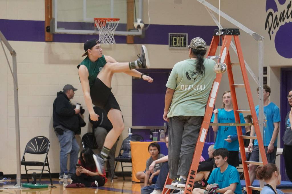 An athlete leaps up to perform the one-foot high kick during the Kahtnuhtana Hey Chiula Native Youth Olympics Invitational at Skyview Middle School near Soldotna, Alaska, on Sunday, Jan. 26, 2025. (Jake Dye/Peninsula Clarion)