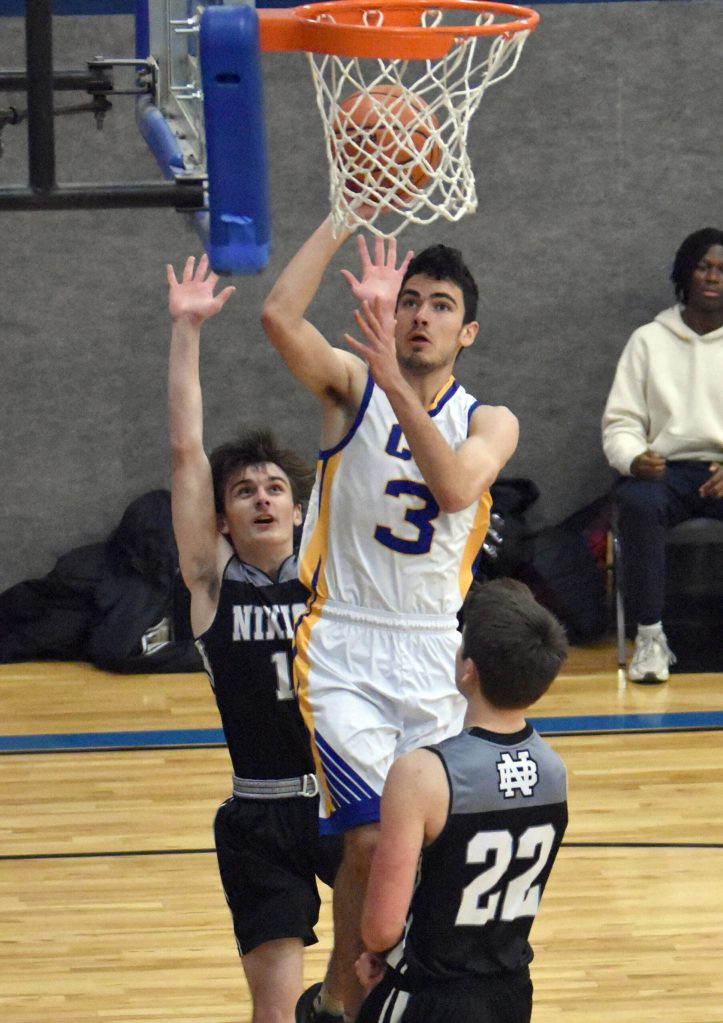 Ian McGarry of Cook Inlet Academy drives against Carter Eiter and Ryder Maguire of Nikiski on Tuesday, Jan. 28, 2025, at Cook Inlet Academy just outside of Soldotna, Alaska. (Photo by Jeff Helminiak/Peninsula Clarion)