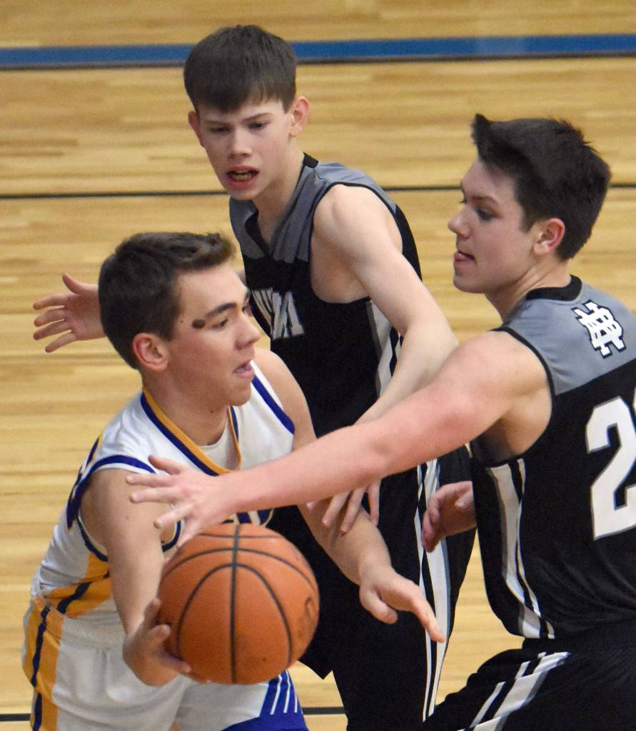 Owen Braband of Cook Inlet Academy faces pressure from Kaleb Allen and Ryder Maguire of Nikiski on Tuesday, Jan. 28, 2025, at Cook Inlet Academy just outside of Soldotna, Alaska. (Photo by Jeff Helminiak/Peninsula Clarion)
