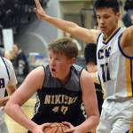 Nikiski's Kameron Bird attacks the defense of Matthew Phillips and Lucas Oyoumick of Cook Inlet Academy on Tuesday, Jan. 28, 2025, at Cook Inlet Academy just outside of Soldotna, Alaska. (Photo by Jeff Helminiak/Peninsula Clarion)