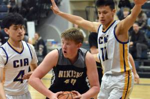 Nikiski's Kameron Bird attacks the defense of Matthew Phillips and Lucas Oyoumick of Cook Inlet Academy on Tuesday, Jan. 28, 2025, at Cook Inlet Academy just outside of Soldotna, Alaska. (Photo by Jeff Helminiak/Peninsula Clarion)